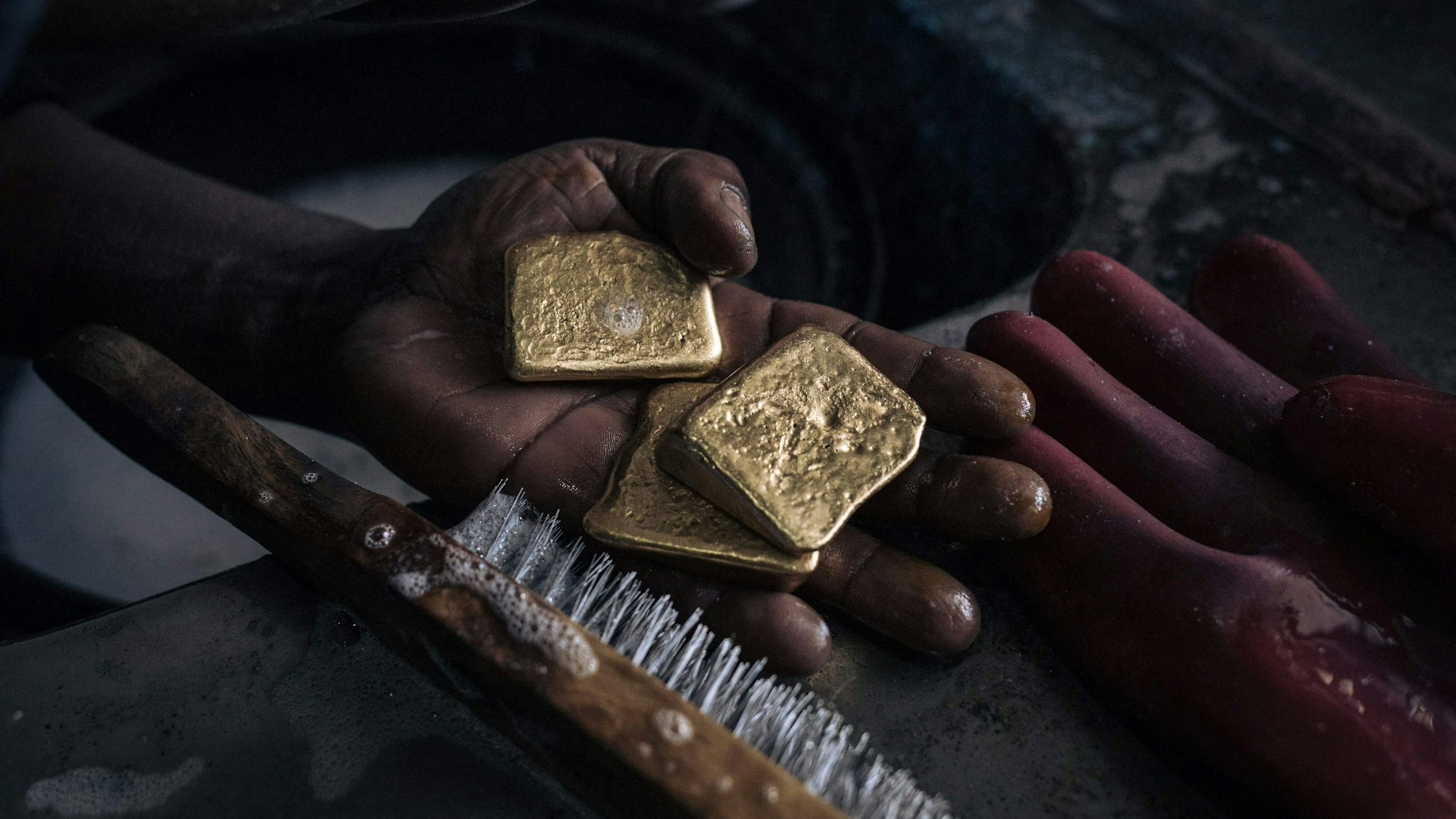 In einer Hand liegt Gold, das mit einer Bürste gereinigt wird. (Symbolbild)