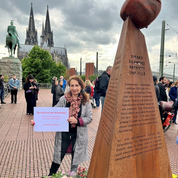 Eine Demonstrantin steht vor einer Erinnerungsstele an den Völkermord an Armeniern im Osmanischen Reich.