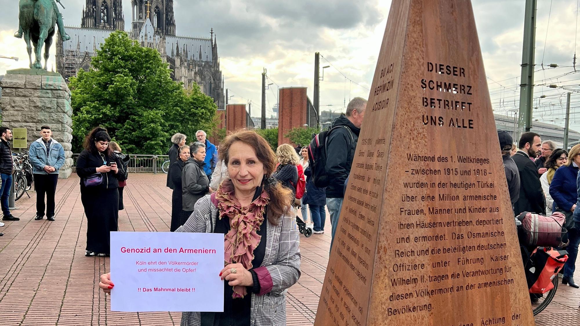 Eine Demonstrantin steht vor einer Erinnerungsstele an den Völkermord an Armeniern im Osmanischen Reich.