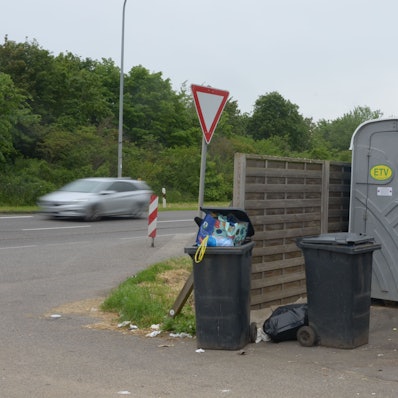 Das Bild zeigt zwei volle Mülltonnen und zwei mobile Toiletten im Euskirchener Industriepark.