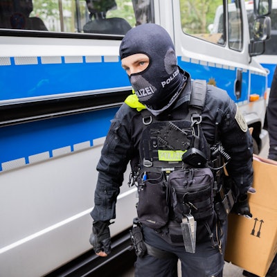Polizisten tragen bei einer Hausdurchsuchung in Berlin-Kreuzberg einen Karton zu einem Fahrzeug. Polizei und Staatsanwaltschaft haben im Zuge eines Ermittlungsverfahrens zu Mitgliedern der „Letzten Generation“ 15 Objekte in sieben Bundesländern durchsucht.