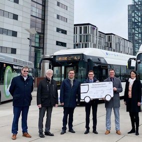 Es sind sieben Personen zu sehen. Zwei von ihnen halten einen großen Förderbescheid.