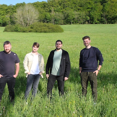 Das Bild zeigt die fünf jungen Musiker der Band „Amie & Me“  auf einer grünen Wiese.