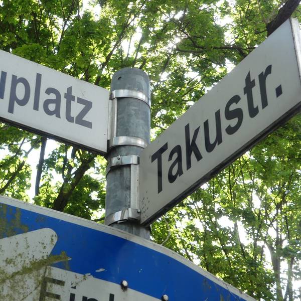 Zwei Straßenschilder hängen an einem Mast.