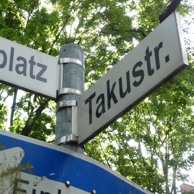 Zwei Straßenschilder hängen an einem Mast.