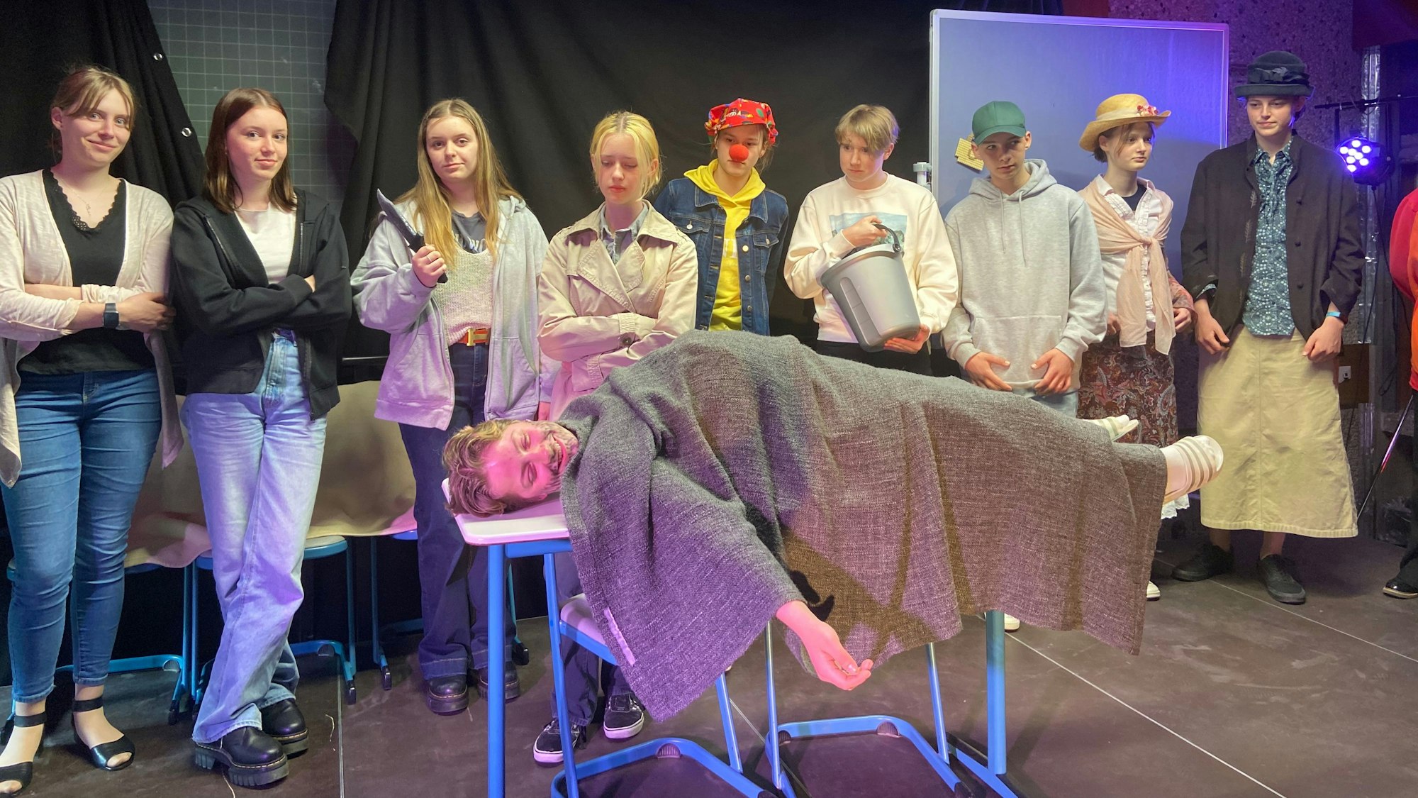 Maja Fleßenkämper liegt auf einem Tisch, die anderen Schülerinnen und Schüler stehen drumherum.