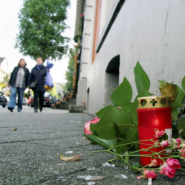 An dem Tatort steht eine Kerze neben Blumen, die auf dem Boden liegen.
