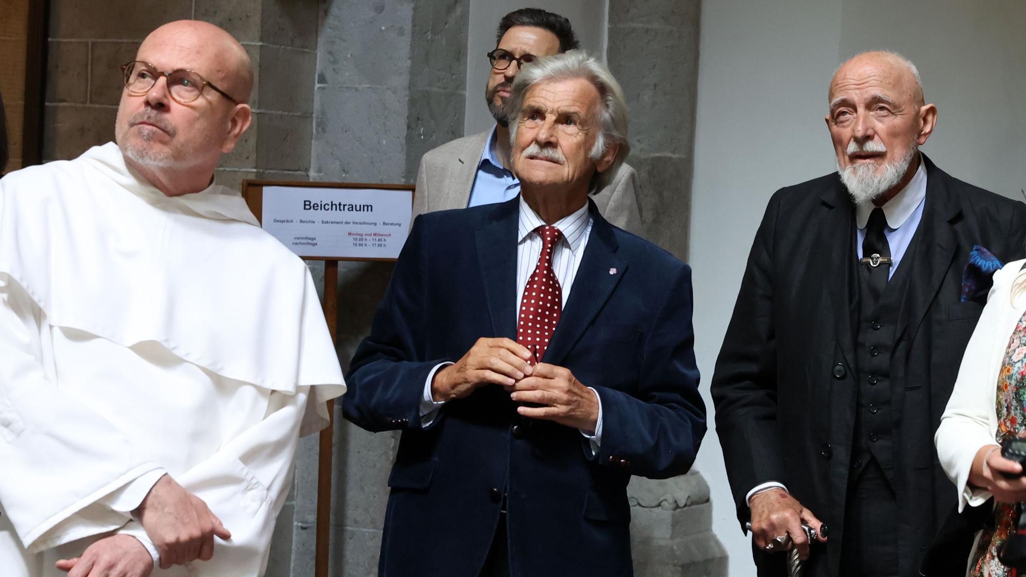 Drei Männer schauen zum Bild heraus und betrachten ein Kirchenfenster des Künstlers Markus Lüpertz.