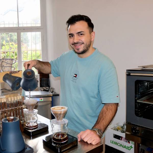 Ein junger Mann füllt heißes Wasser in eine Kaffeekanne mit Filter.