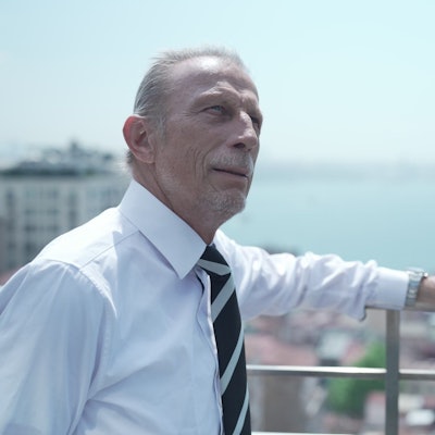 Ex-Fußballtrainer Christoph Daum steht an einem Geländer und blickt in die Ferne. Er trägt ein Hemd und Krawatte.