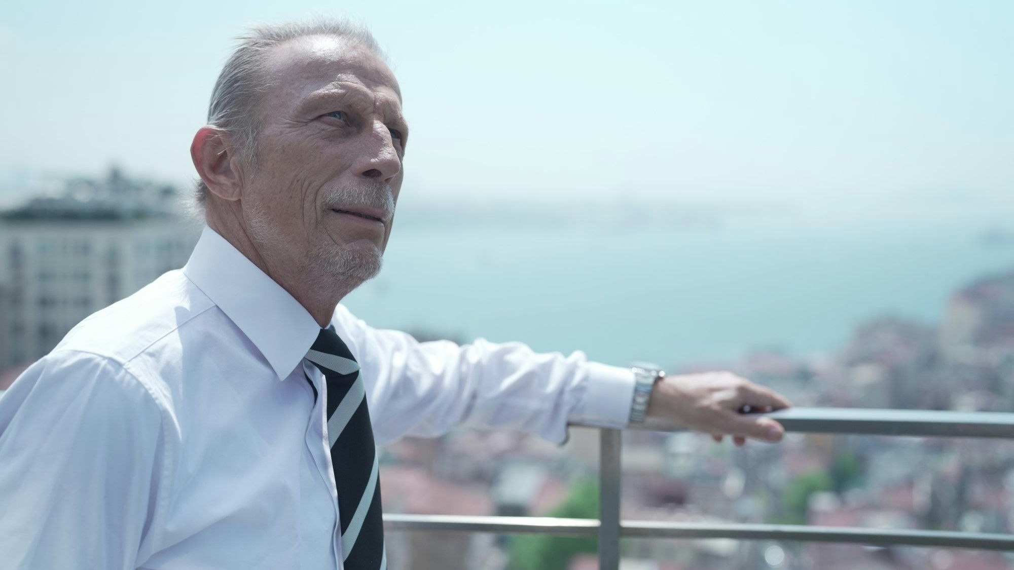 Ex-Fußballtrainer Christoph Daum steht an einem Geländer und blickt in die Ferne. Er trägt ein Hemd und Krawatte.
