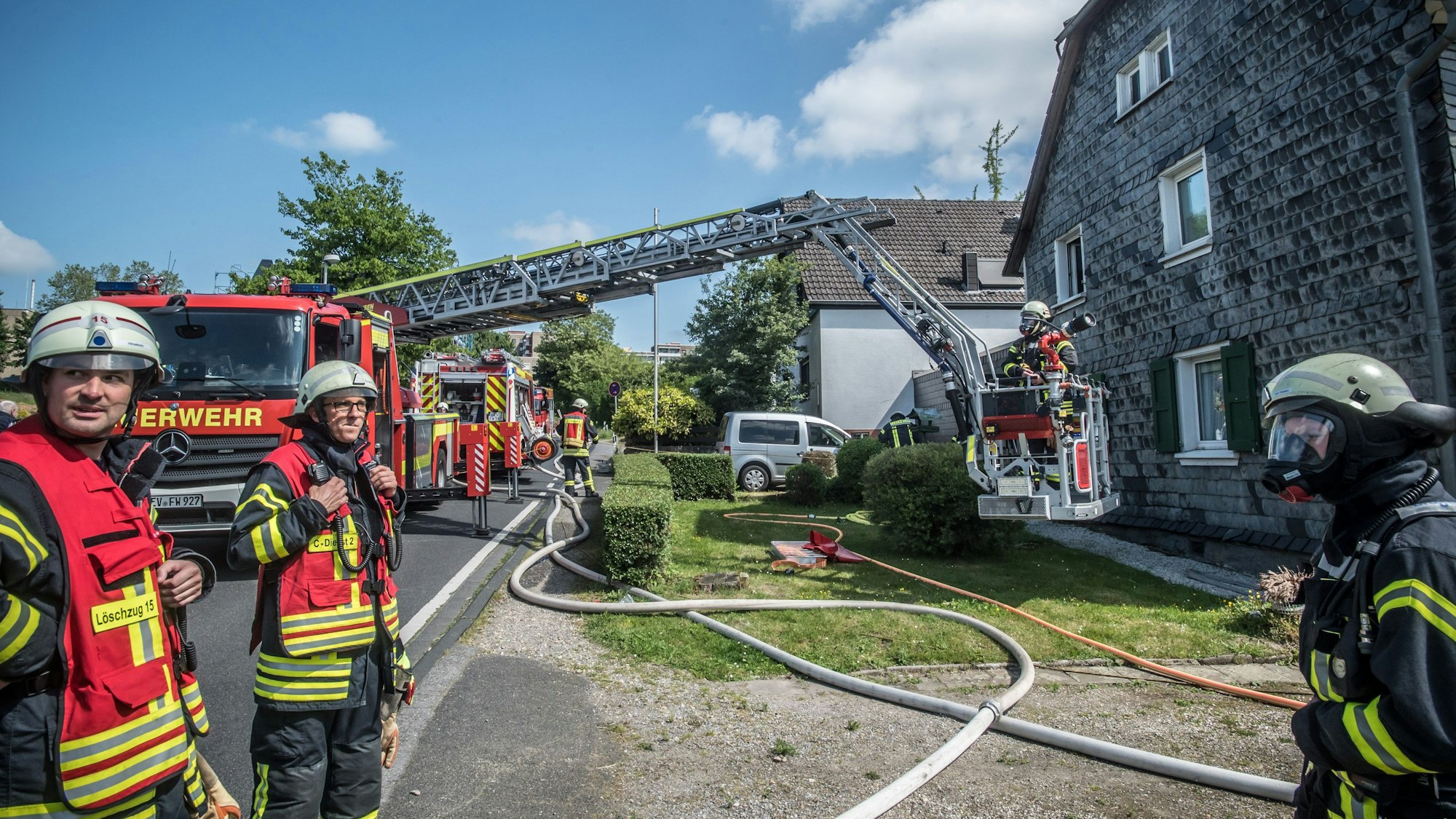 Feuerwehrleute vor einem verschieferten Haus in Steinbüchel
