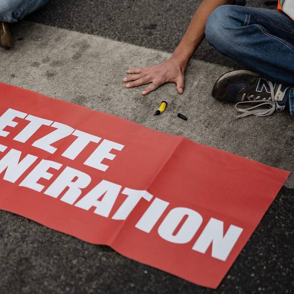 Ein Aktivist der Gruppe „Letzte Generation“, der seine Hand selbst auf der Straße festgeklebt hat, blockiert eine Kreuzung am Geismar Tor.