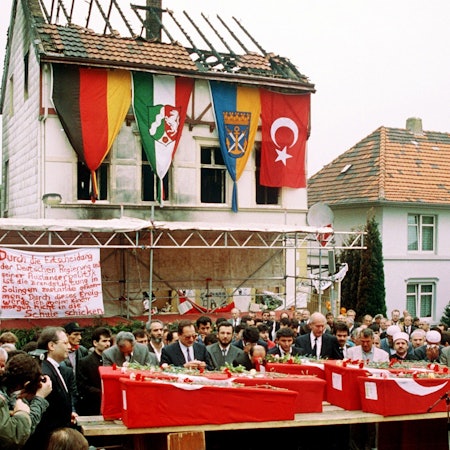 Das Foto zeigt die Särge von fünf Türkinnen vor dem ausgebrannten Haus in Solingen bei einer Trauerfeier.