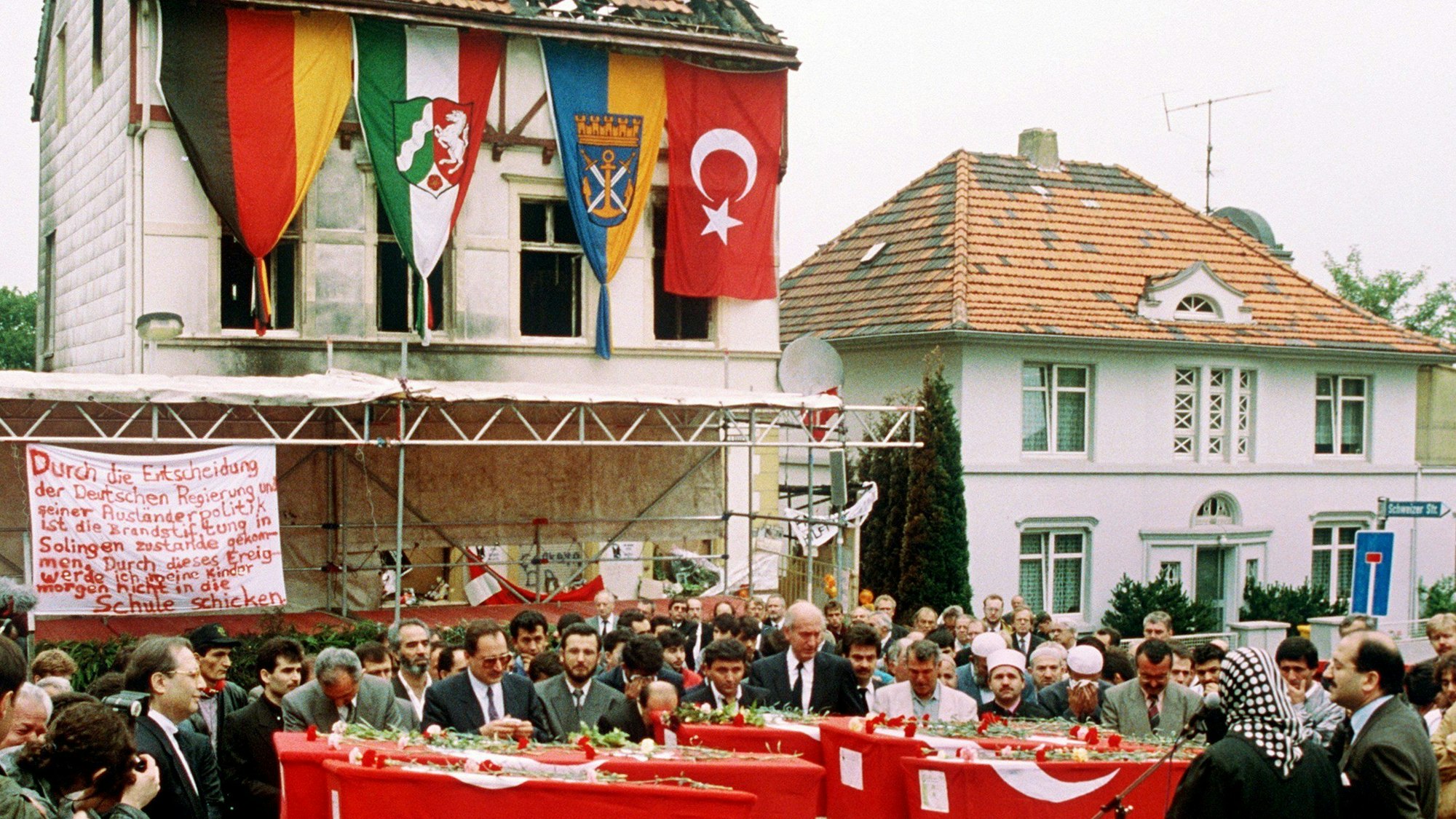 Das Foto zeigt die Särge von fünf Türkinnen vor dem ausgebrannten Haus in Solingen bei einer Trauerfeier.