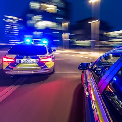 Zwei Polizeiwagen rasen mit Blaulicht durch die Nacht.