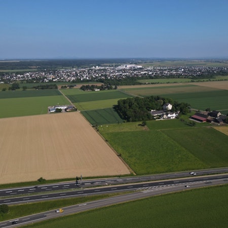 Im Bereich von Gut Neuheim, an der A1, wird auf einer Fläche von 6,3 Hektar ein Solarpark entstehen. Die Luftaufnahme zeigt das Areal, im Hintergrund ist Weilerswist zu erkennen.