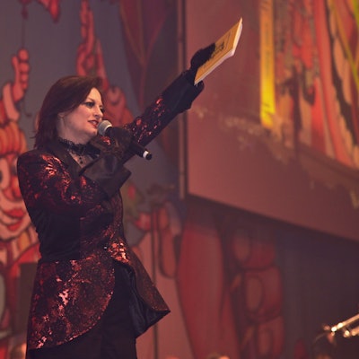 Eine verkleidete Moderatorin steht bei einer Karnevalsveranstaltung auf der Bühne.