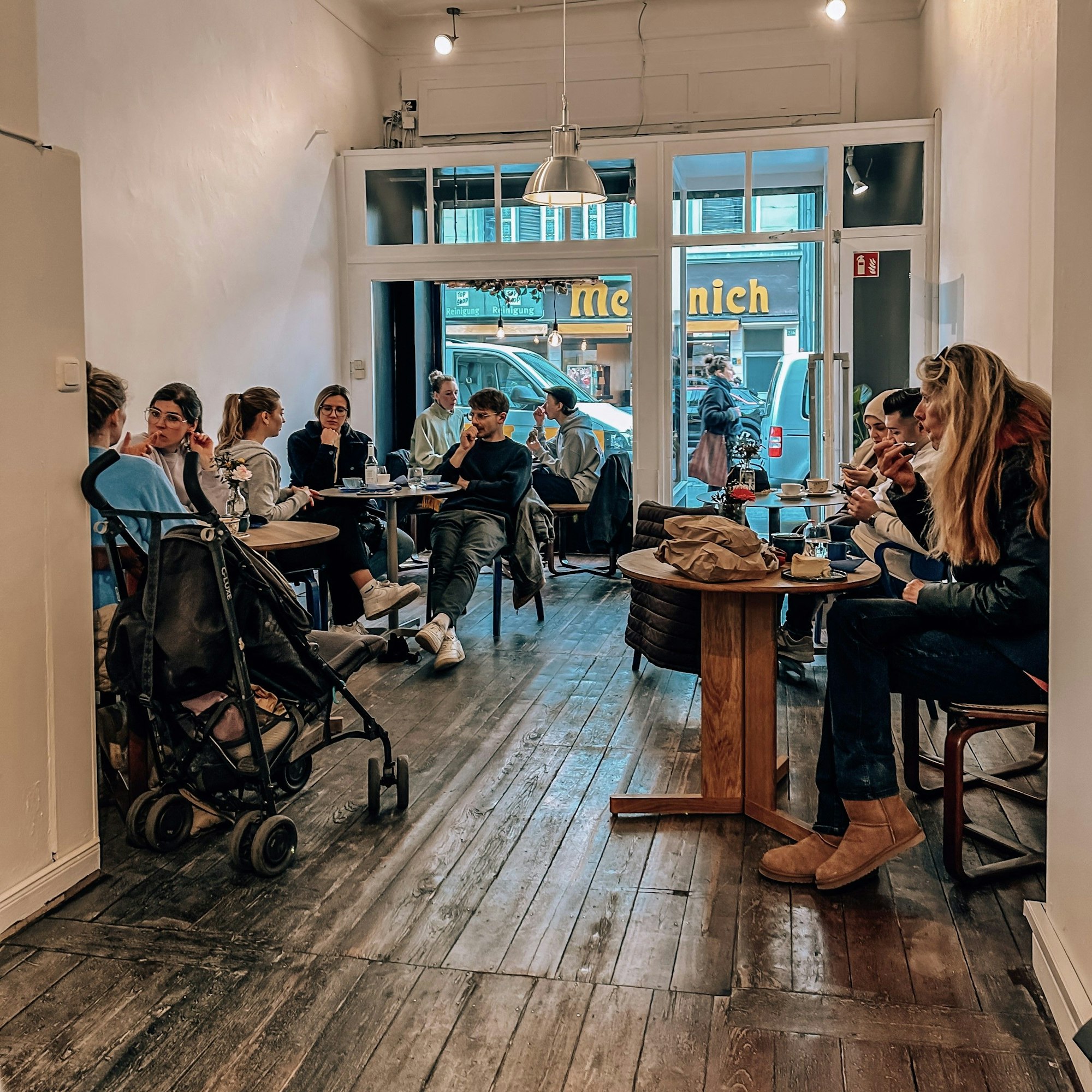 In dem Café mit dem alten Holzboden stehen Stühle und Tische links und rechts an der Wand.