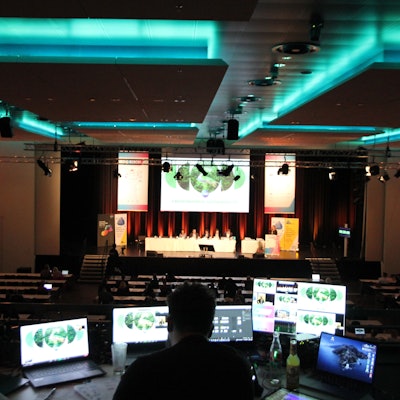 Ein Mann sitzt vor mehreren Bildschirmen in einem abgedunkelten Saal.