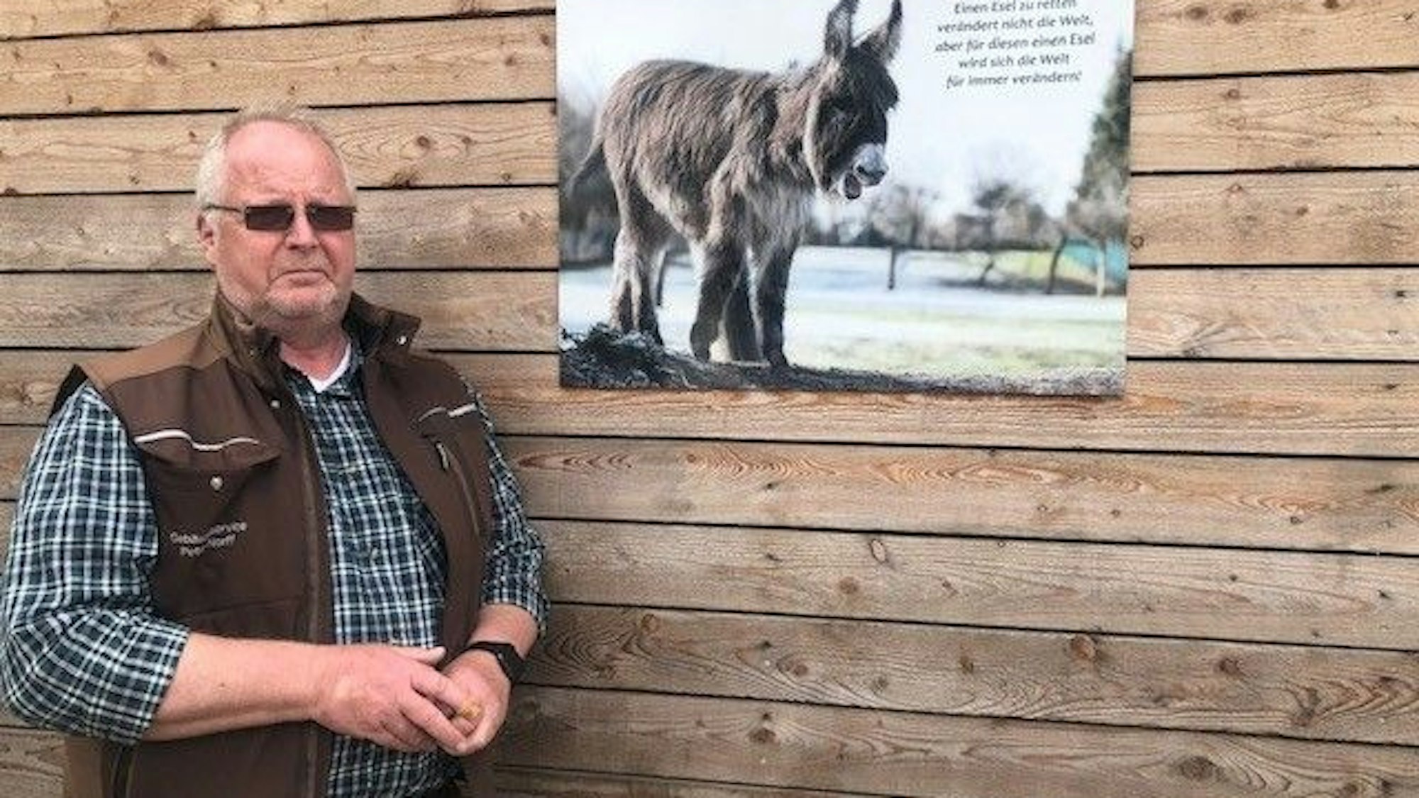 Der Gründer des „Eselpark Zons e.V“ Peter Norff steht vor einer Holzwand