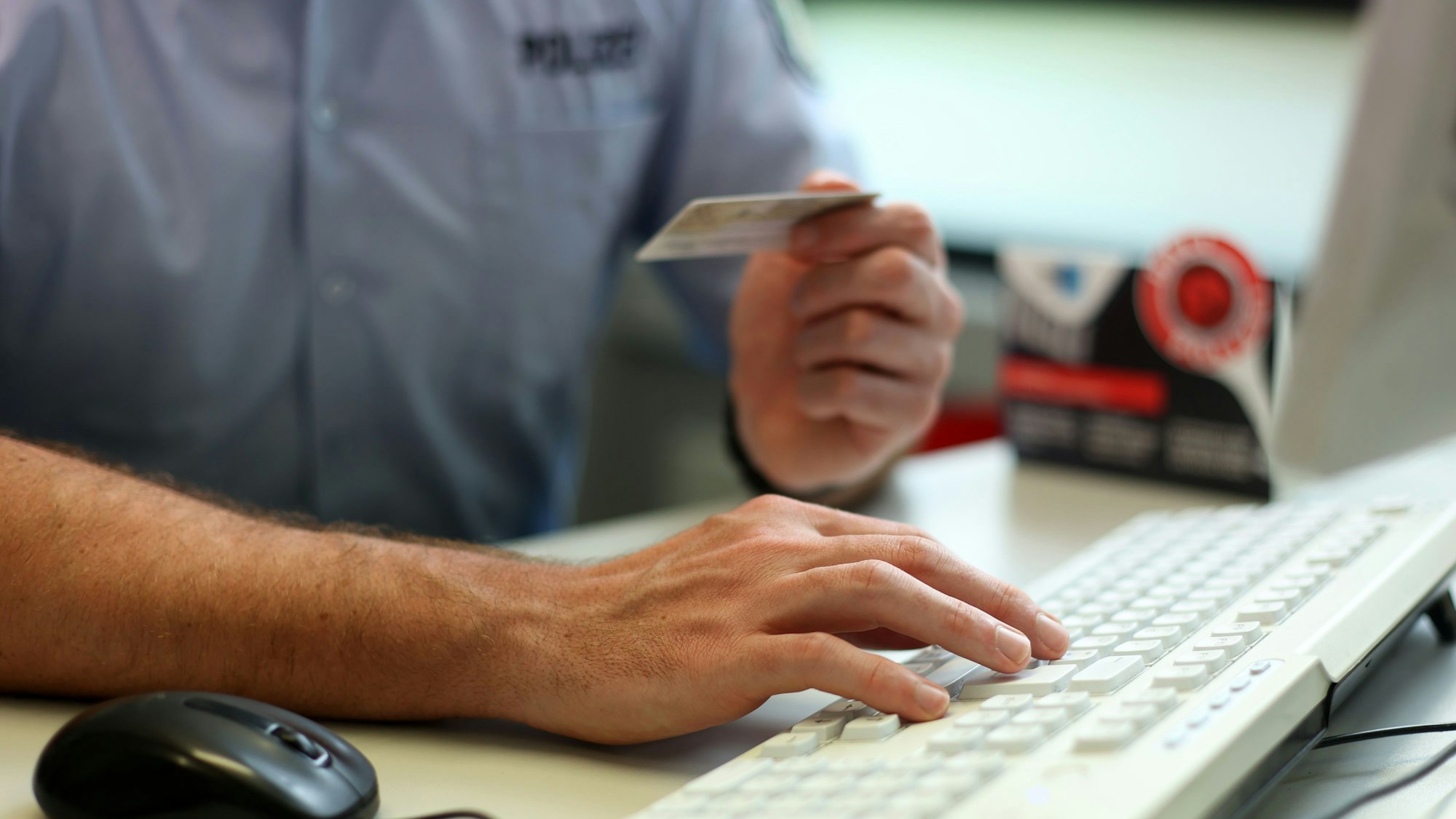 Ein Streifenpolizist gibt Daten von einem Personalausweis in den Polizeicomputer ein.