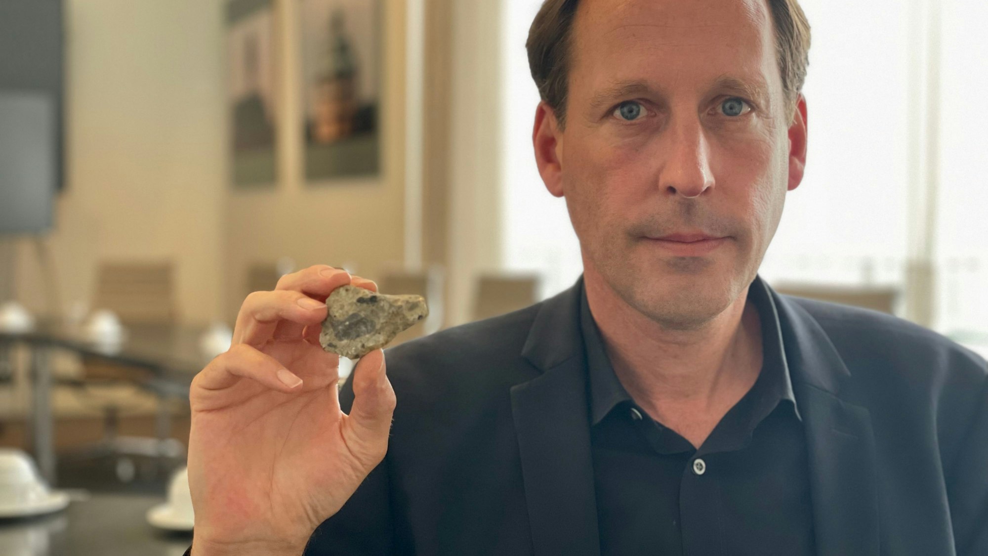 Grünen-Abgeordneter Engstfeld hält einen kleinen Brocken der Rahmedetalbrücke in die Kamera