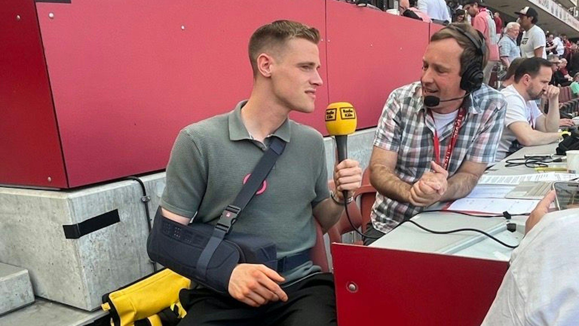 Steffen Tigges zeigt sich frisch an der Schulter operiert im Stadion am Mikrofon von Radio Köln.