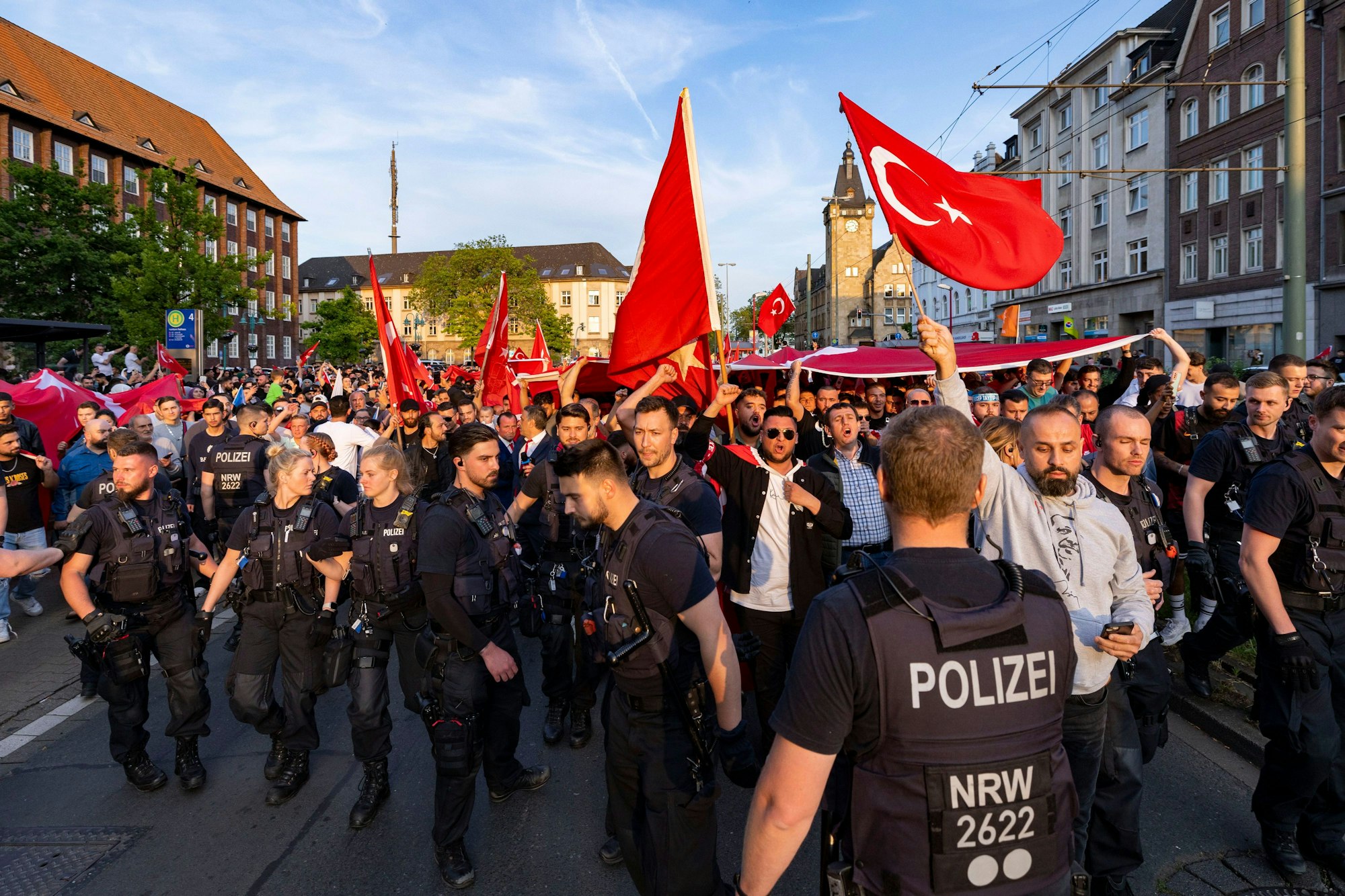 Einsatzkräfte der Polizei begleiten Anhänger des türkischen Präsidenten Erdogan im Duisburger Norden, die noch vor dem amtlichen Ergebnis der Stichwahl in der Türkei, mit türkischen Nationalfahnen durch die Straßen gezogen sind.