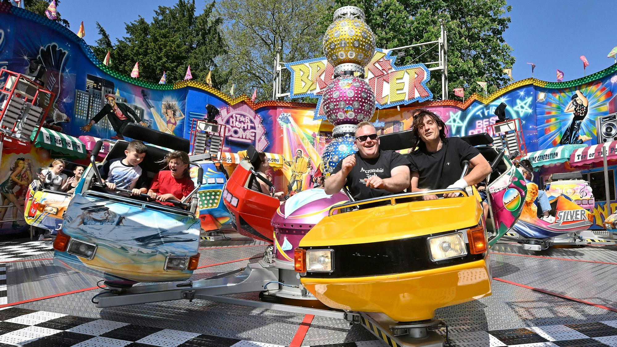 Im Kirmesfahrgeschäft Break Dancer vergnügen sich Menschen bei Sonnenschein und strahlend blauem Himmel.