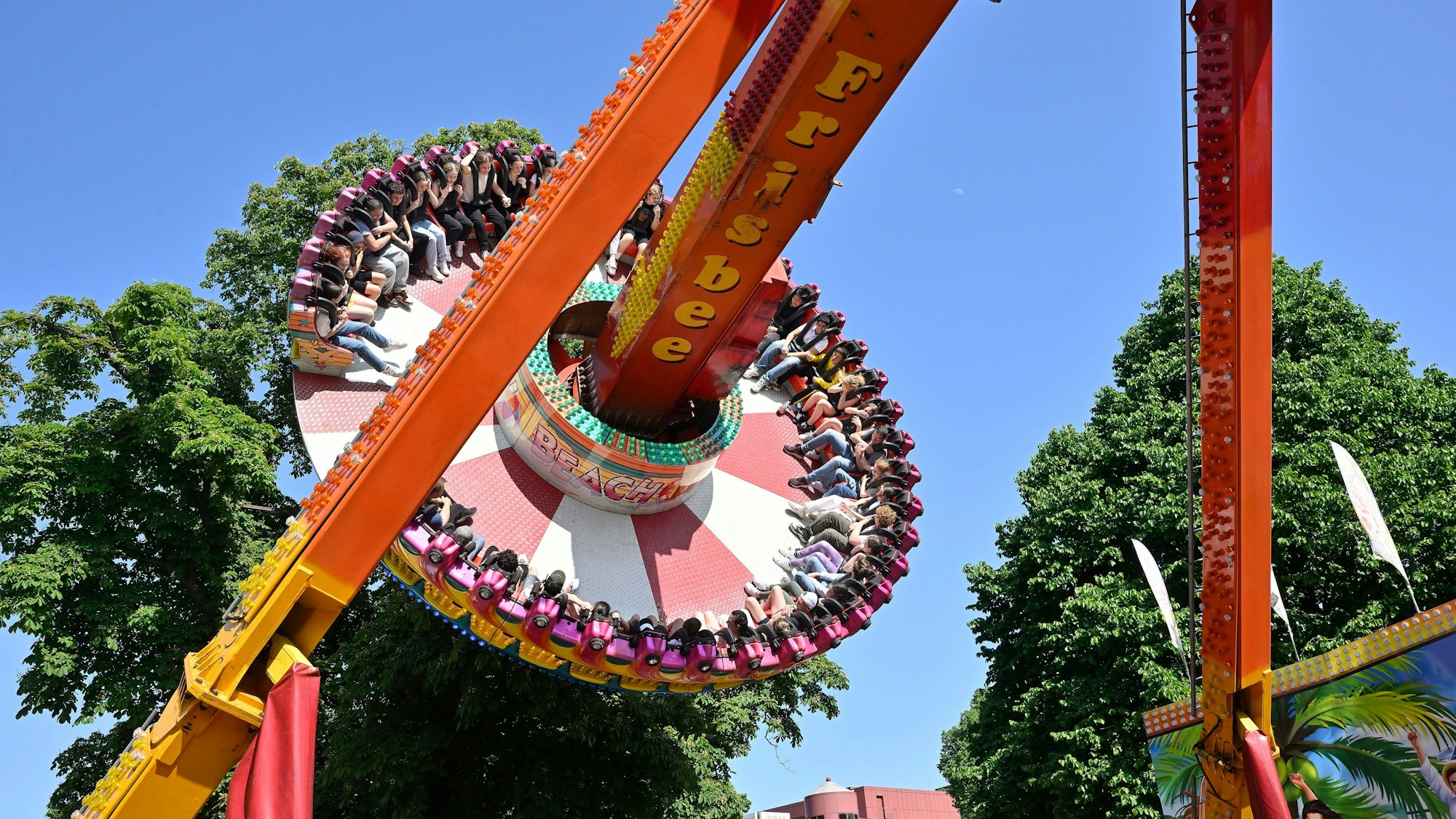 Menschen sitzen in Sitzen auf einer Scheibe, die hoch hinaus in die Luft gewirbelt wird.
