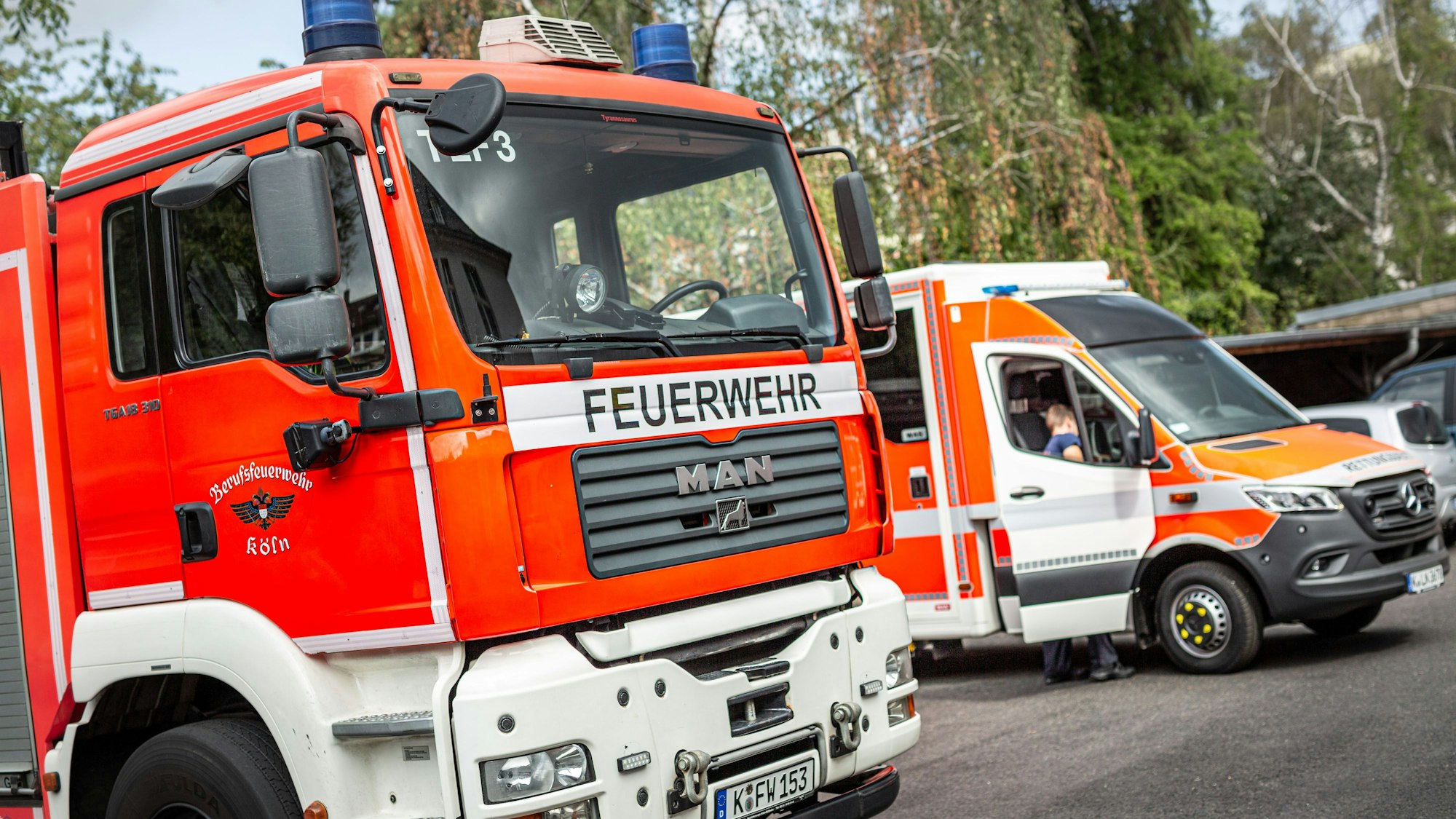 Ein Tanklöschfahrzeug (TLF) und ein Rettungswagen der Berufsfeuerwehr Köln steht auf dem Hof einer Feuerwache.