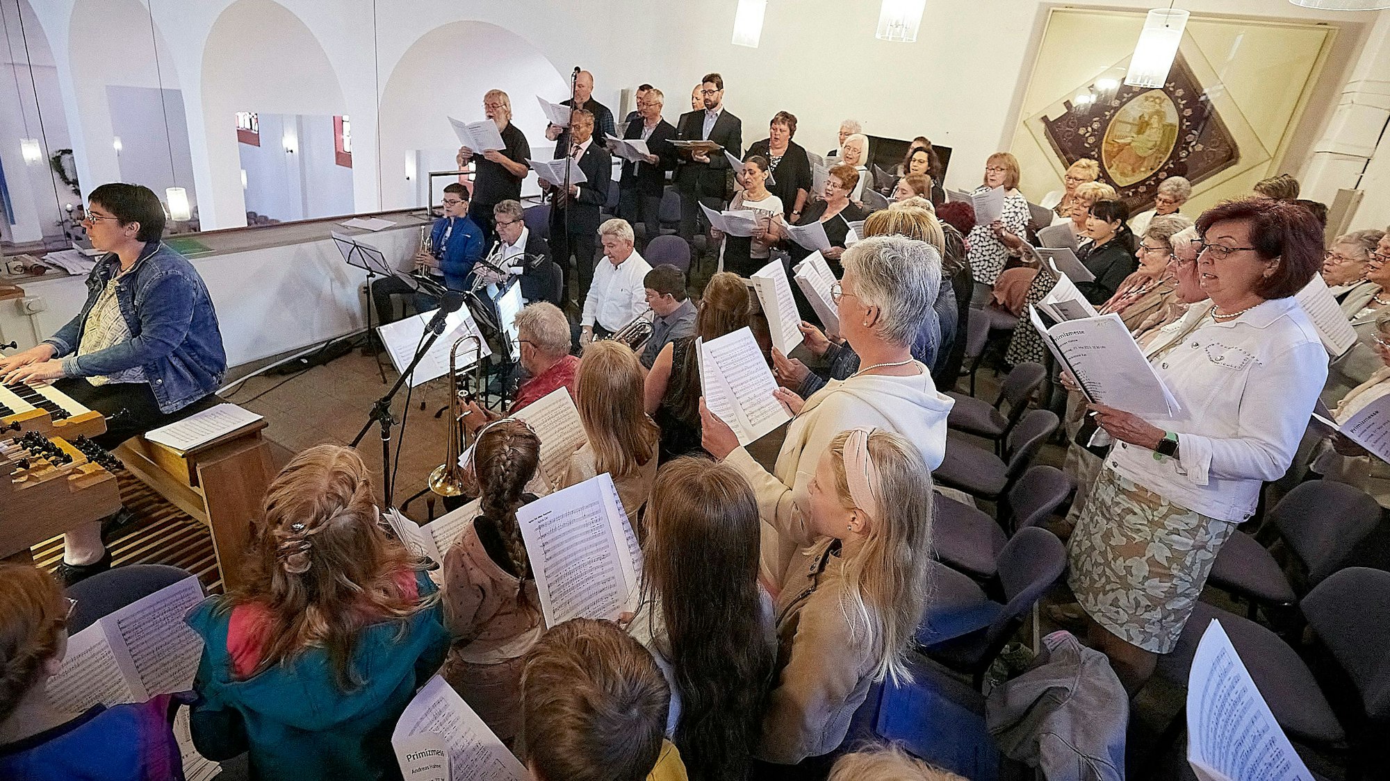 Das Bild zeigt verschiedene Chöre und eine Organistin auf der Empore der Kaller Kirche.