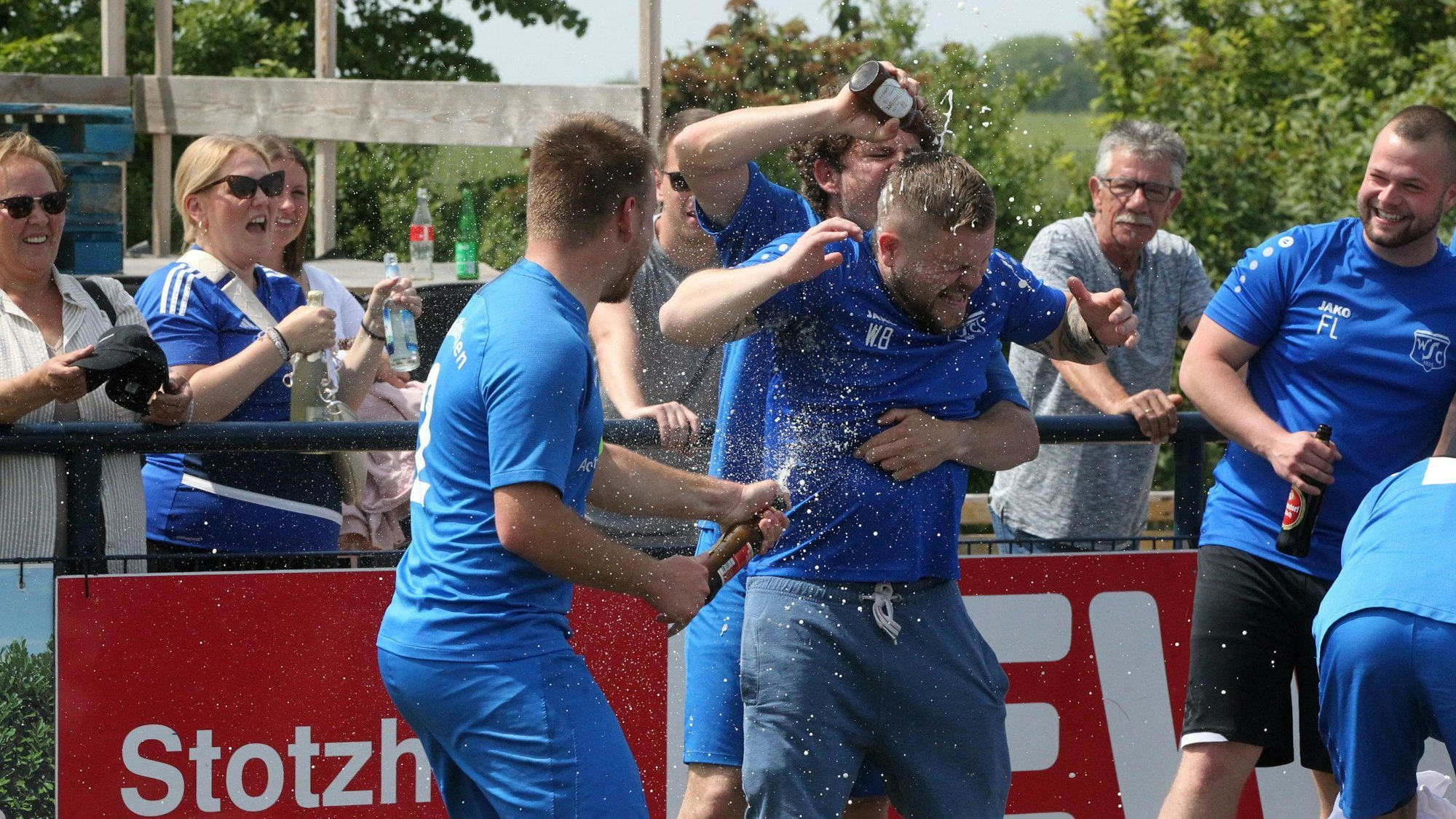 Stotzheims Trainer Wolfgang Botzian erhält von zwei Spielern eine Bierdusche.