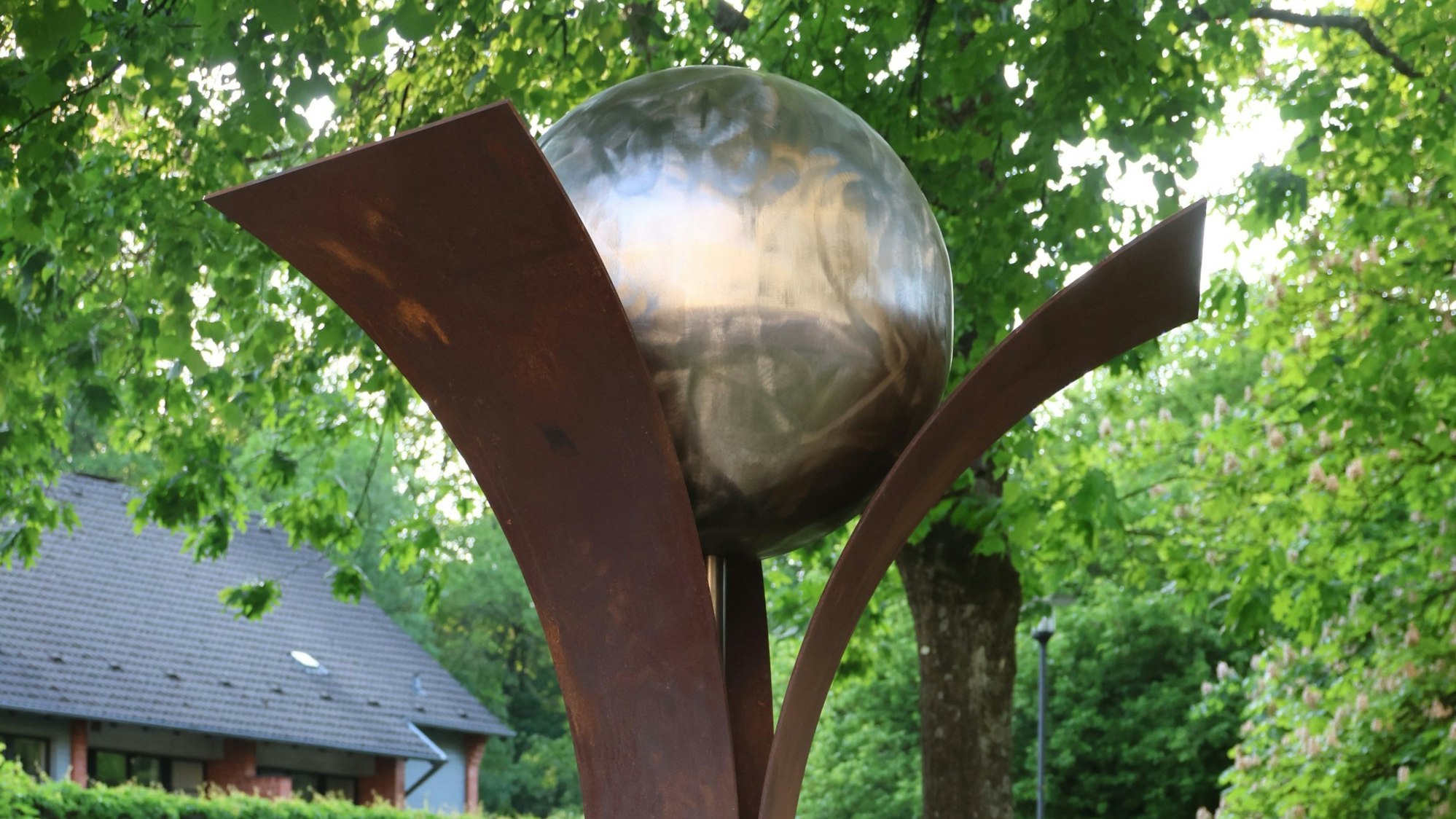 Drei Stahlbänder, die Engelskirchen, Plan-de-Cuques und Mogilno symbolisieren, tragen eine Weltkugel.