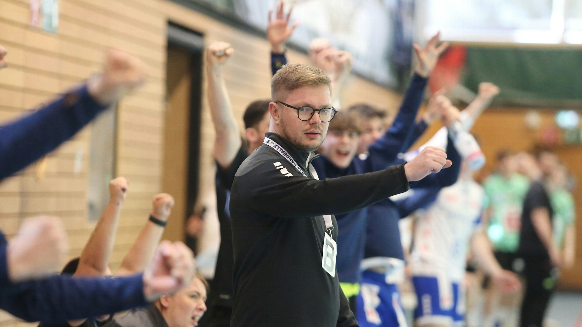 Ein Handball-Trainer steht am Rand und coacht sein Team.