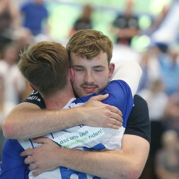 Zwei Handballspieler umarmen sich.