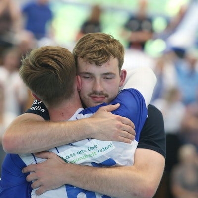 Zwei Handballspieler umarmen sich.