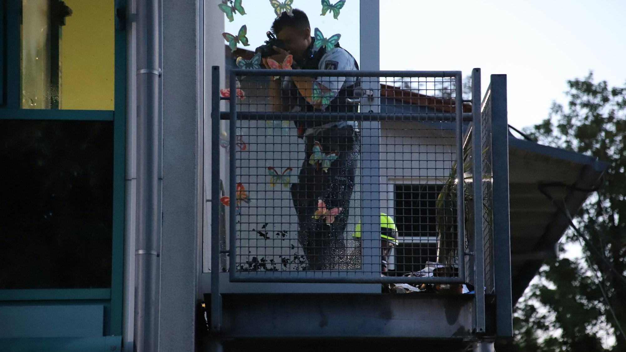 Ein Polizist fotografiert die offene Türe der Schule.