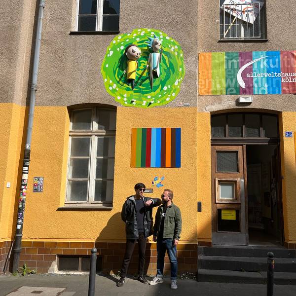 Yaşar Fidan (l.) und Lemi Karaca von Coach e.V. stehen vor ihrem Kunstwerk am Allerweltshaus in Ehrenfeld. Die 3D-Installation zeigt Rick und Morty aus der gleichnamigen Serie, wie sie aus einem Portal kommen.