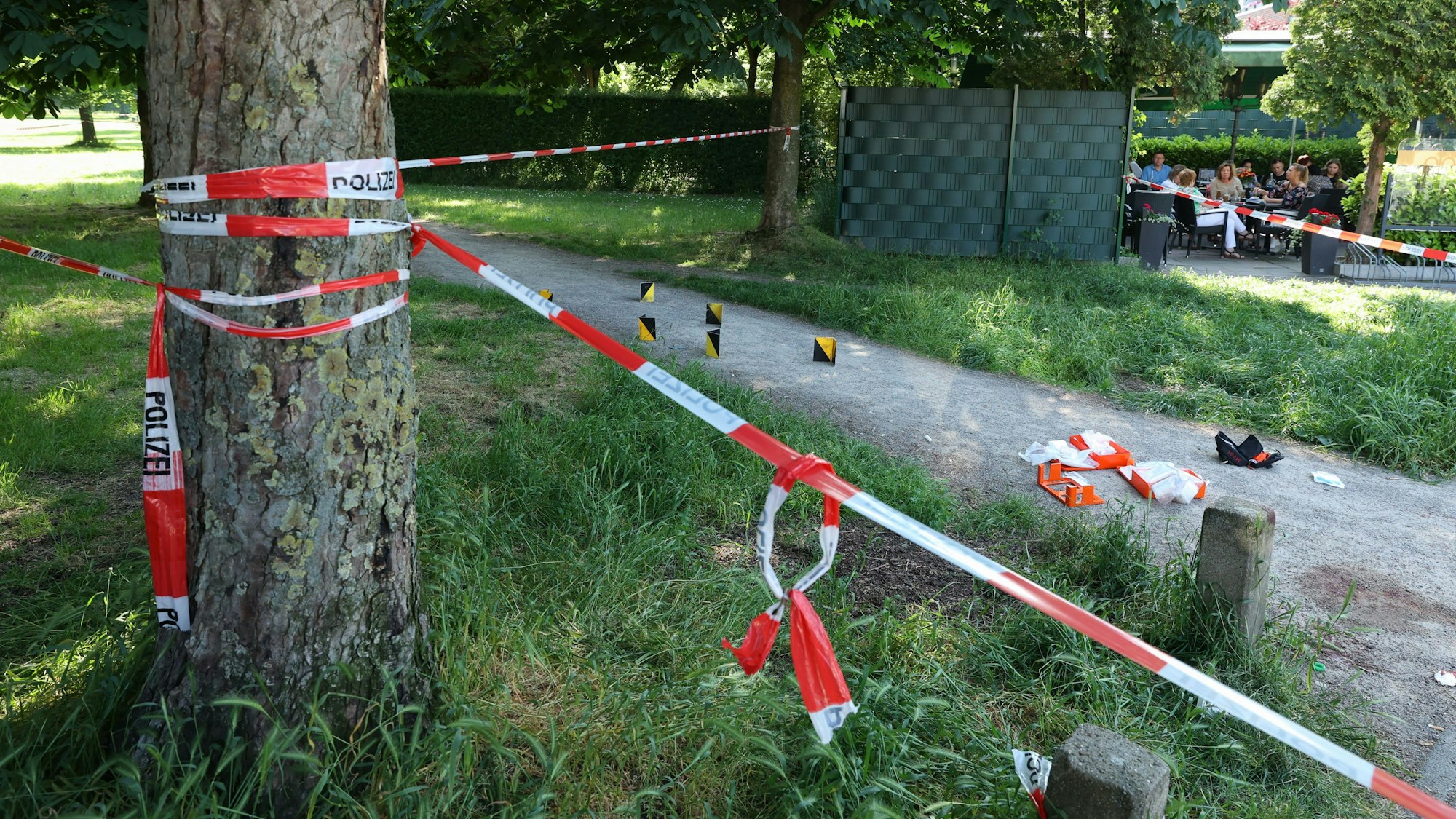 Polizeiabsperrung mit Flatterband direkt neben einem Biergarten am Clevischen Ring in Mülheim.