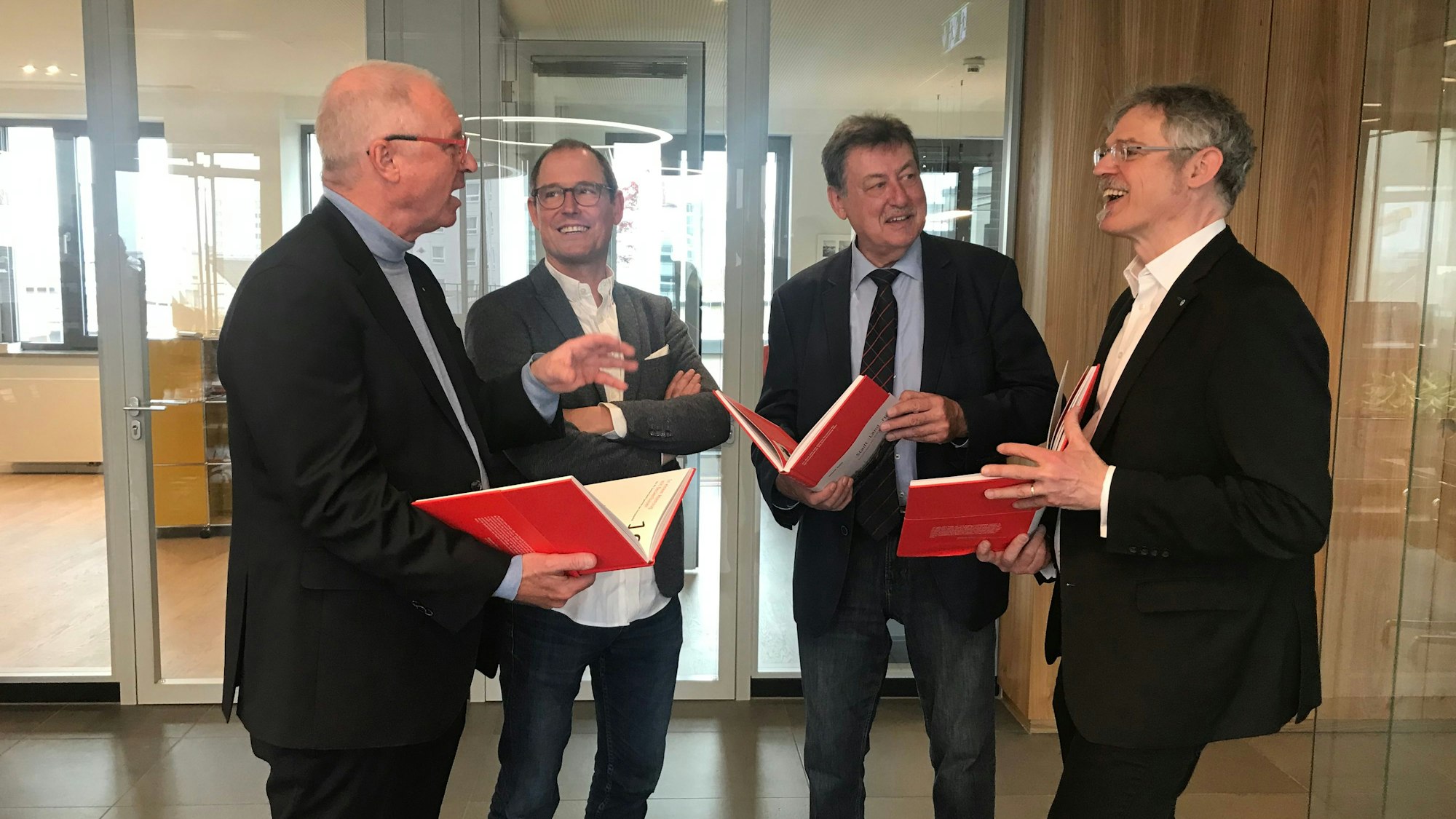 Alexander Wüerst, Vorstandsvorsitzender der Kreissparkasse Köln, Damian van Melis, Geschäftsführer des Greven Verlags, Autor Helmut Gabel und Ulrich Soénius, Direktor des Rheinisch-Westfälischen Wirtschaftsarchivs stehen zusammen und lachen.