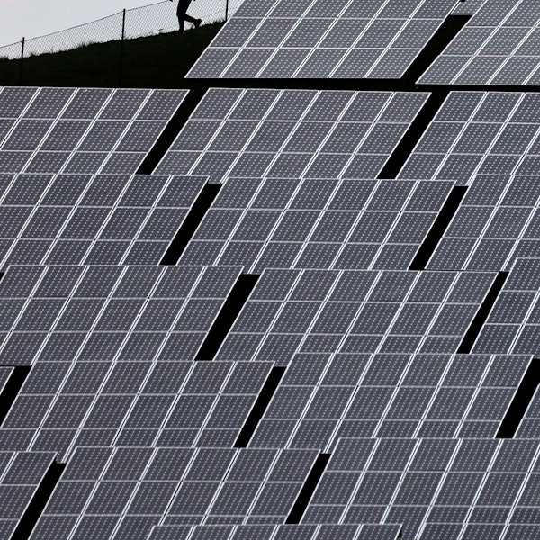 Ein Mensch läuft hinter Solaranlagen her.