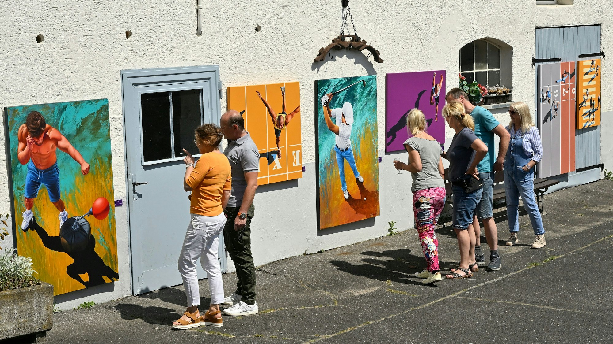 Menschen stehen vor einer Wand, an der Bilder hängen.