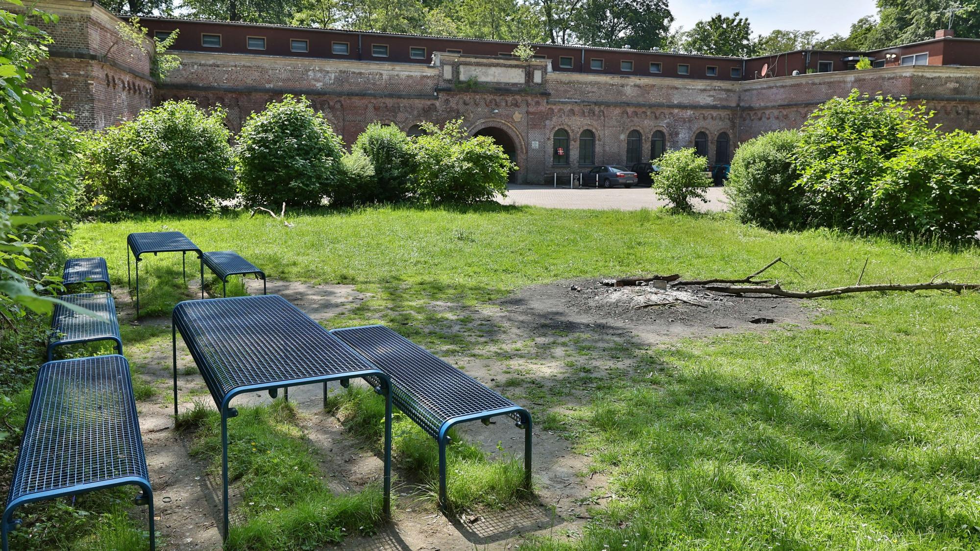 Im Vordergrund sind Bänke und Tische sowie eine Feuerstelle zu sehen, im Hintergrund das Decksteiner Fort.