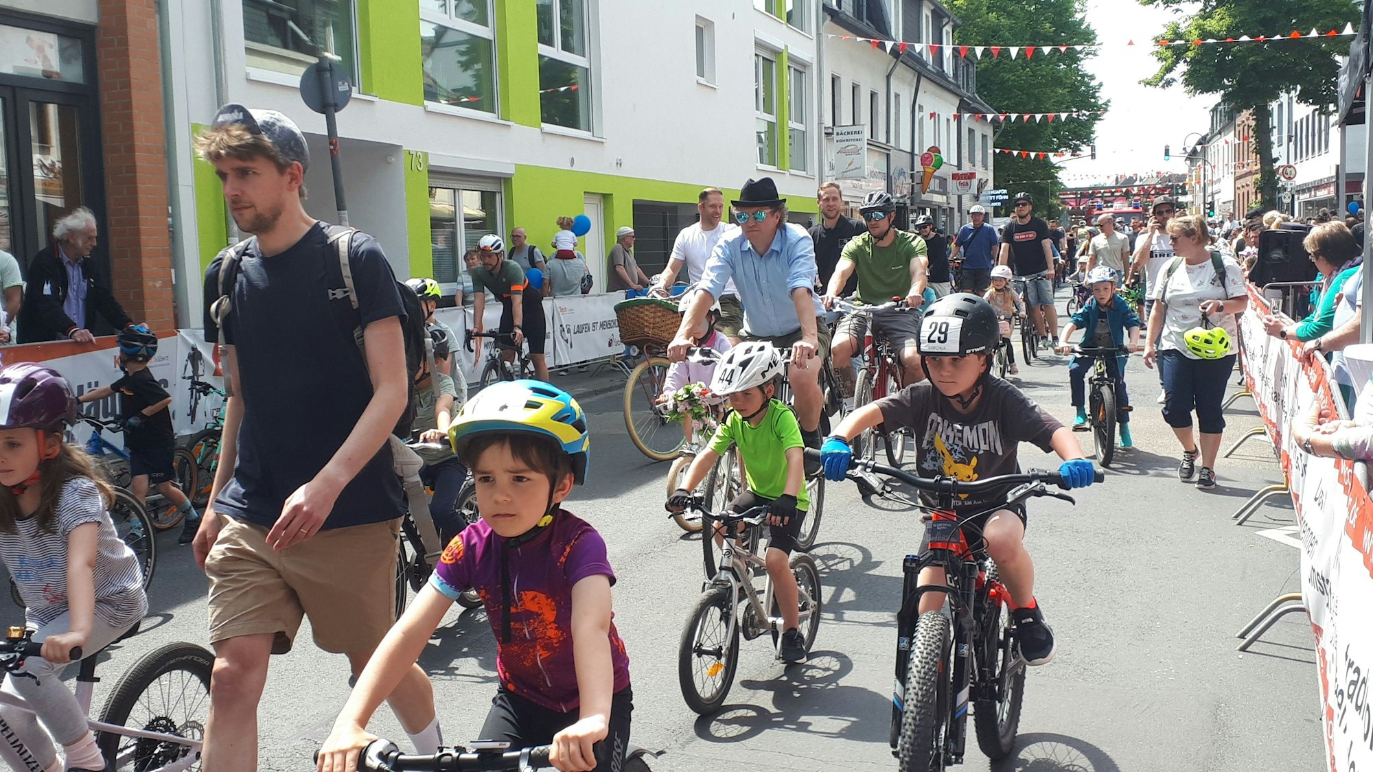 Kidner auf Rädern werden von zu Fuß gehenden oder radelnden Erwachsenen begleitet.