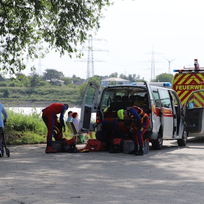 Rettungskräfte ziehen sich bei einem Einsatz an ihren Fahrzeugen um.