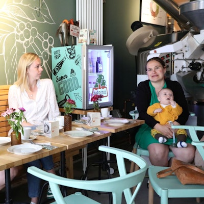 Drei Frauen sitzen an Tischen in der Café-Manufaktur-Rösterei „Taza Azul“, eine hält ihren drei Monate alten Sohn auf ihrem Schoß.