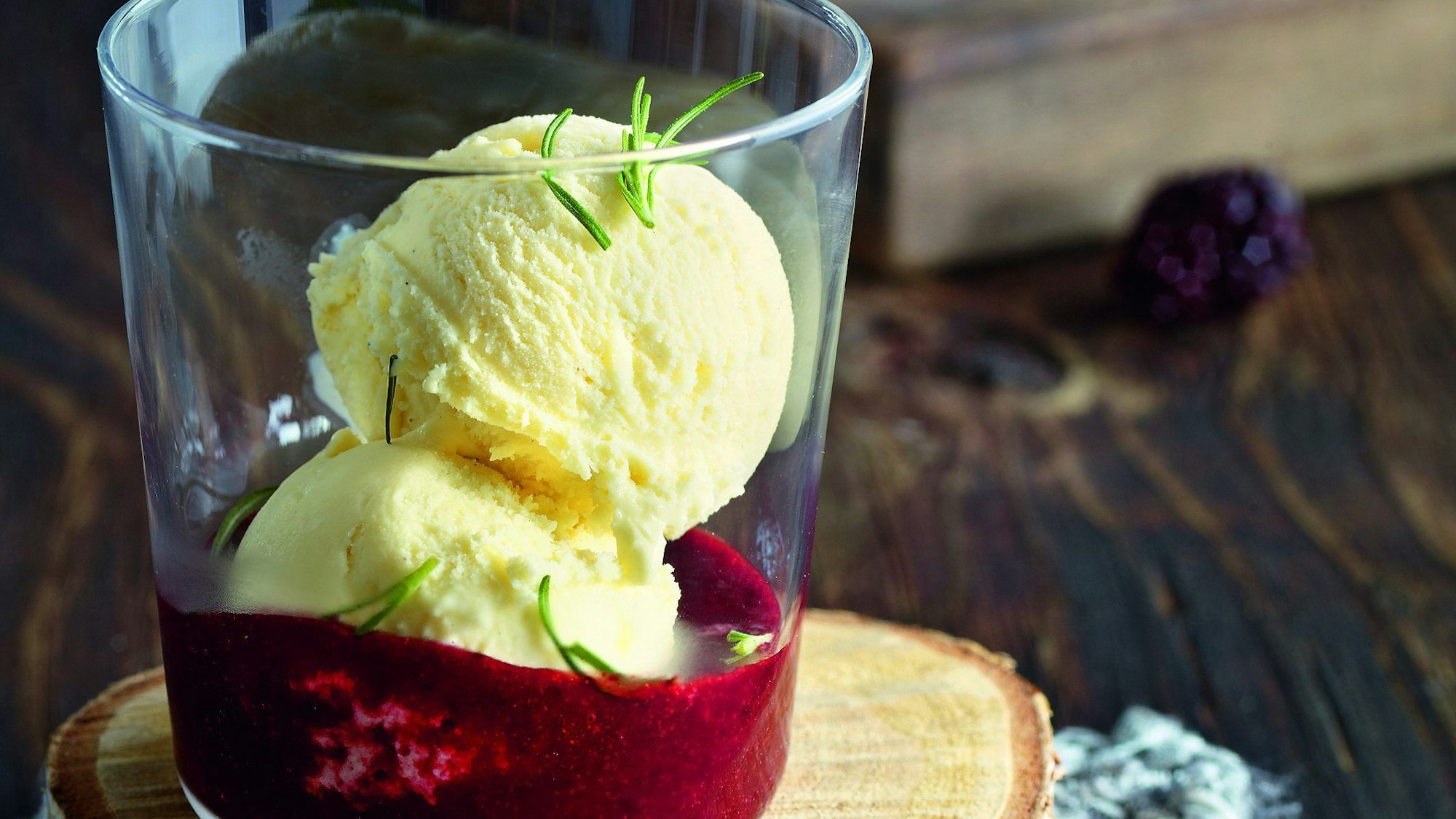 zwei Kugeln Eis in einem Glas auf rotem Püree