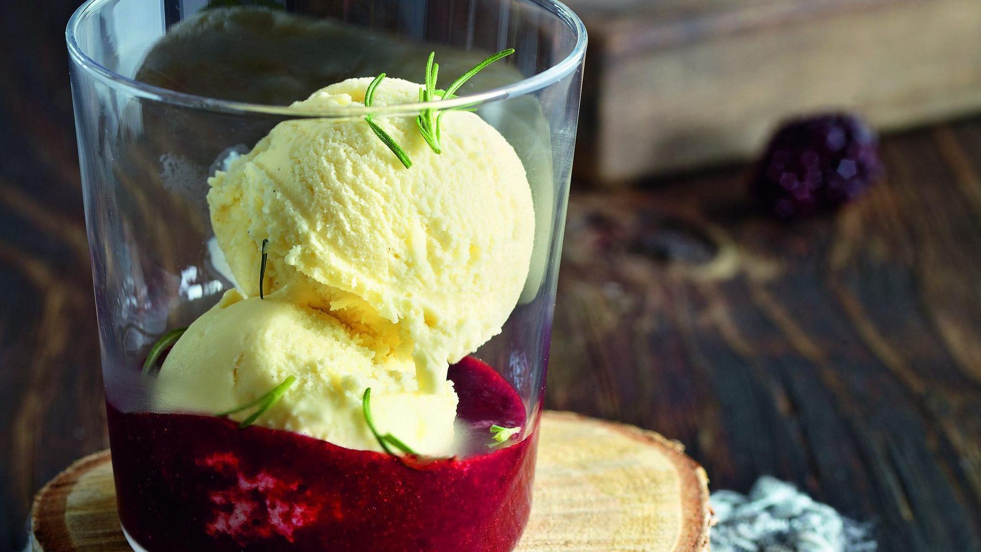 zwei Kugeln Eis in einem Glas auf rotem Püree